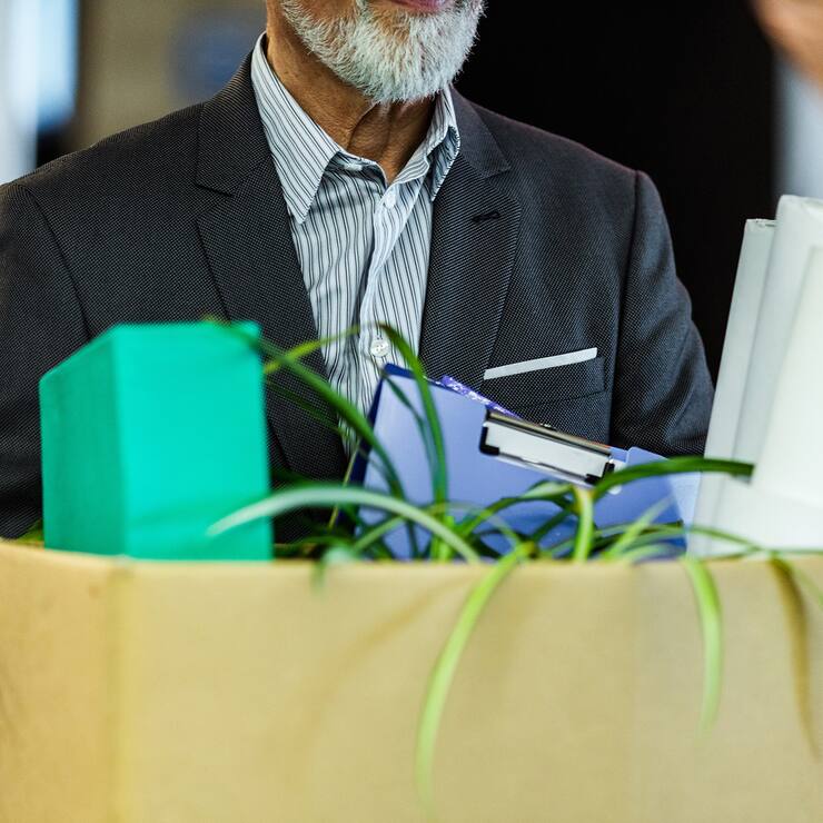 Unrecognizable male entrepreneur carrying his belongings after being fired from his job.