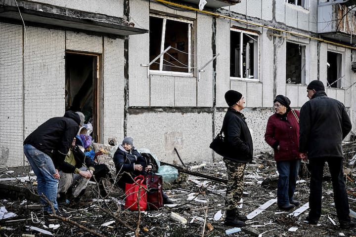 Des habitants devant leur immeuble atteint par un bombardement.